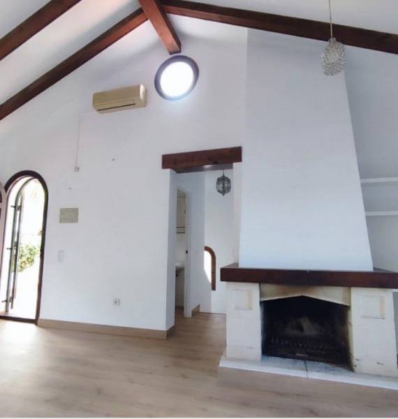 Interior of a family house with a fireplace, wooden beams, and a floor with a wooden decor.