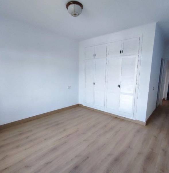 White room in a family house with a wooden decor floor and a built-in wardrobe.