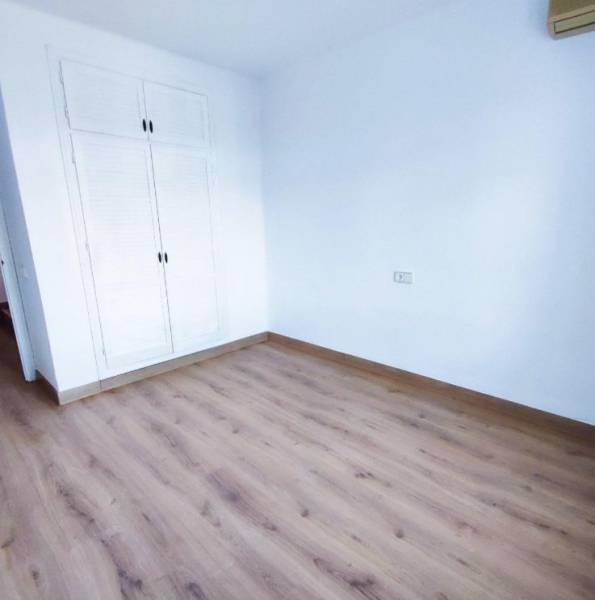 An empty room in a family house with a white wardrobe and a wooden-patterned floor.