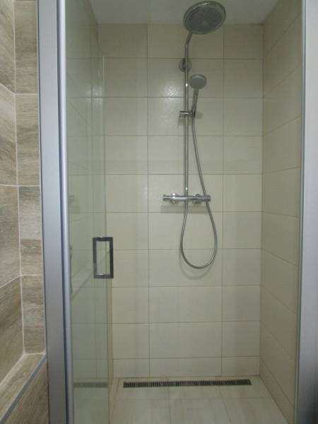 A shower enclosure with glass doors in the bathroom of a 2-room apartment.