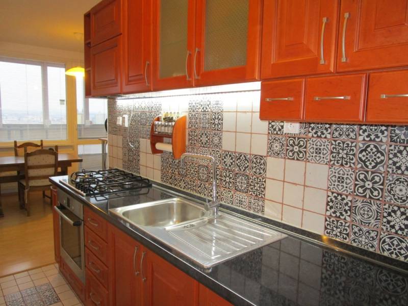 A kitchen with colorful patterns, wooden cabinets, a gas stove, and a dining table in a two-room apartment.