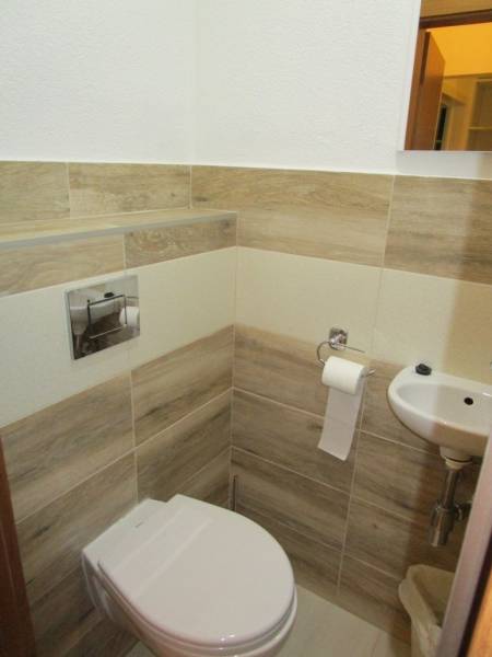Toilet with a sink, wood decor tiles in a 2-room apartment.
