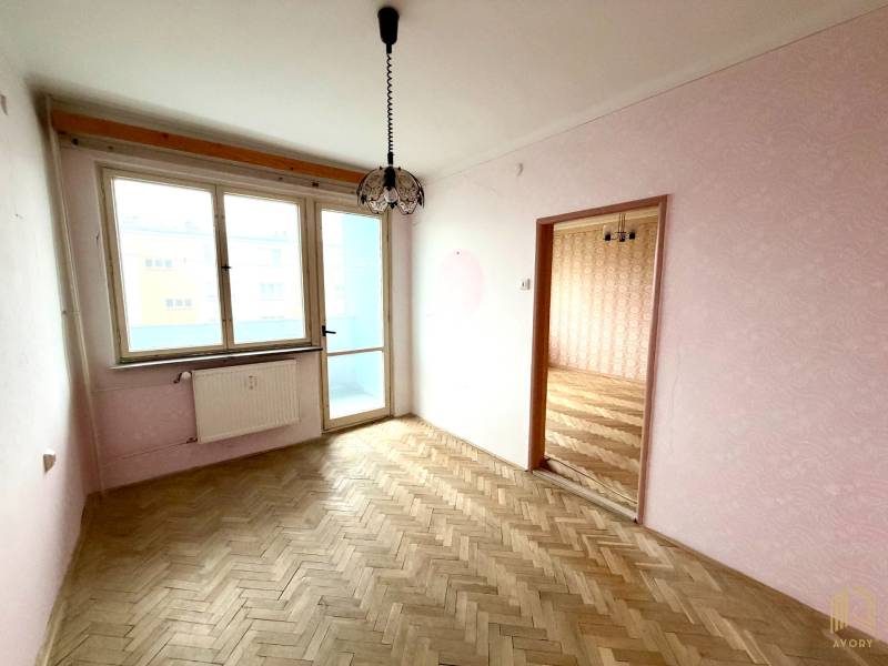 A room with light walls, a balcony, and a wooden decor floor in a 2-room apartment.