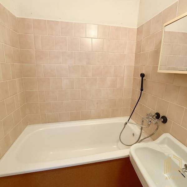 Bathroom with tiles and a bathtub in a 2-room apartment.