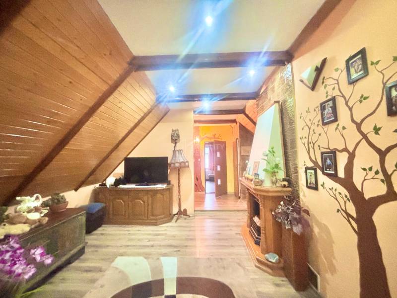 A room in a family house with a wooden decor floor, TV, and wall decorations.