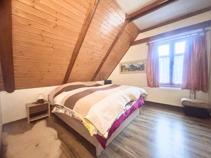 Attic bedroom of a family house with a wooden decor floor and wooden wall paneling.