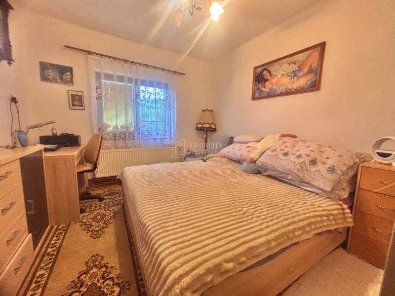 Bedroom in a family house with a bed, a desk, and pictures on the walls.