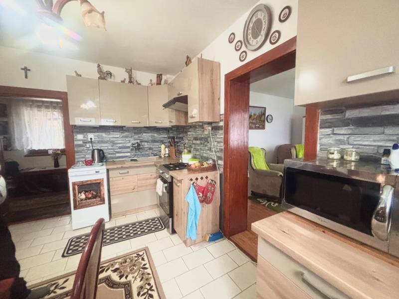 A kitchen in a family house with white tiles and furniture in a wood decor.