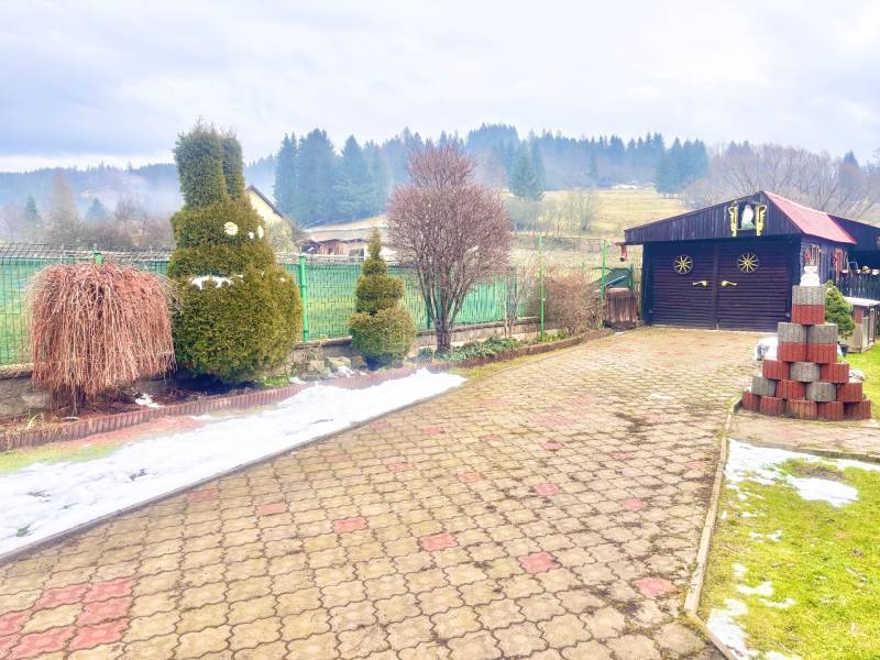 A view of the courtyard of a family house in Predmier in Turzovka with a garden house and trees.