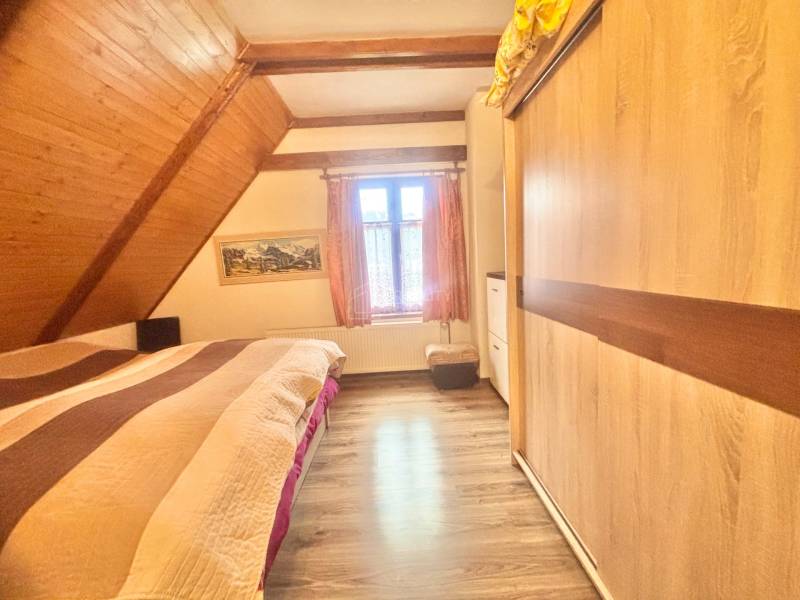 Bedroom in a family house with a wood-decor floor and a slanted wooden ceiling.
