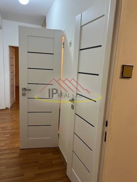 Interior of a 2-room apartment with white doors and a floor with a wooden decor.