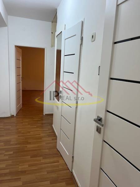 A hallway in a 2-room apartment with a wooden decor floor and white doors.
