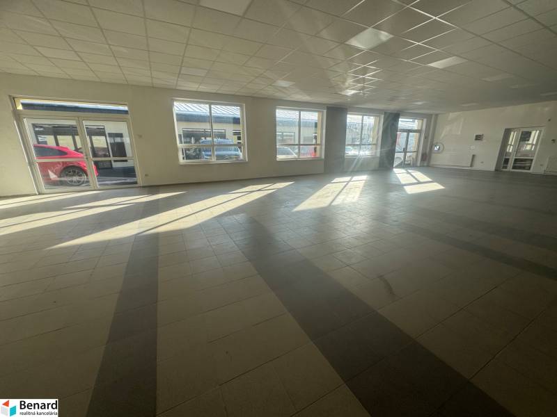 Commercial space with large windows and tiled floors bathed in sunlight.