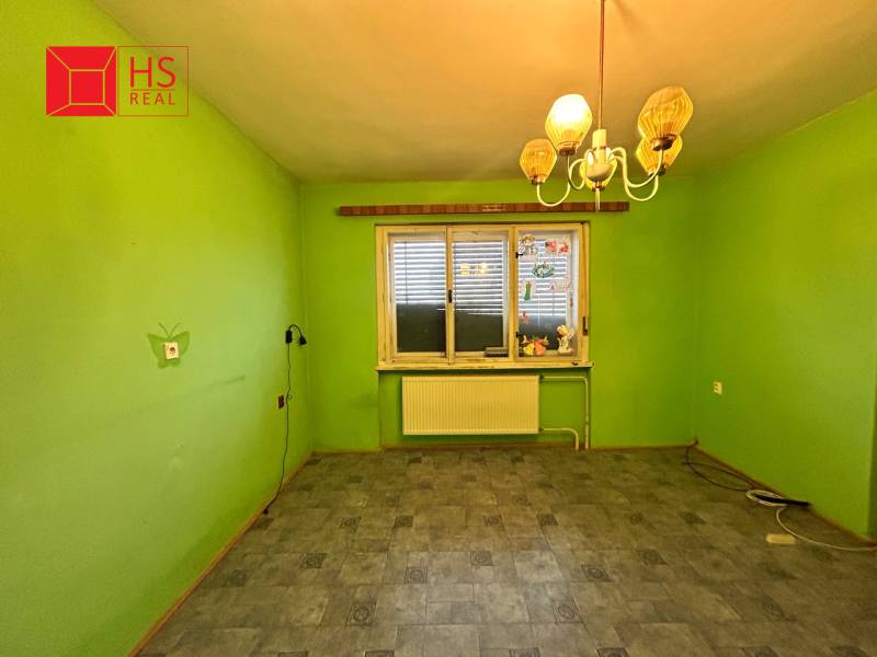 A room in a family house with green walls, a lamp, and a wooden decor floor.