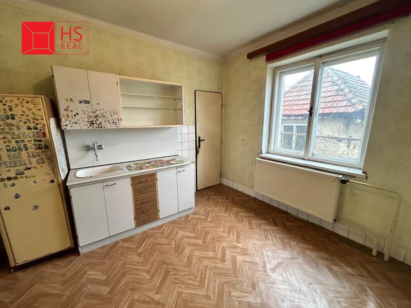 A kitchen in a family house with a wooden decor floor and a simple kitchen unit.