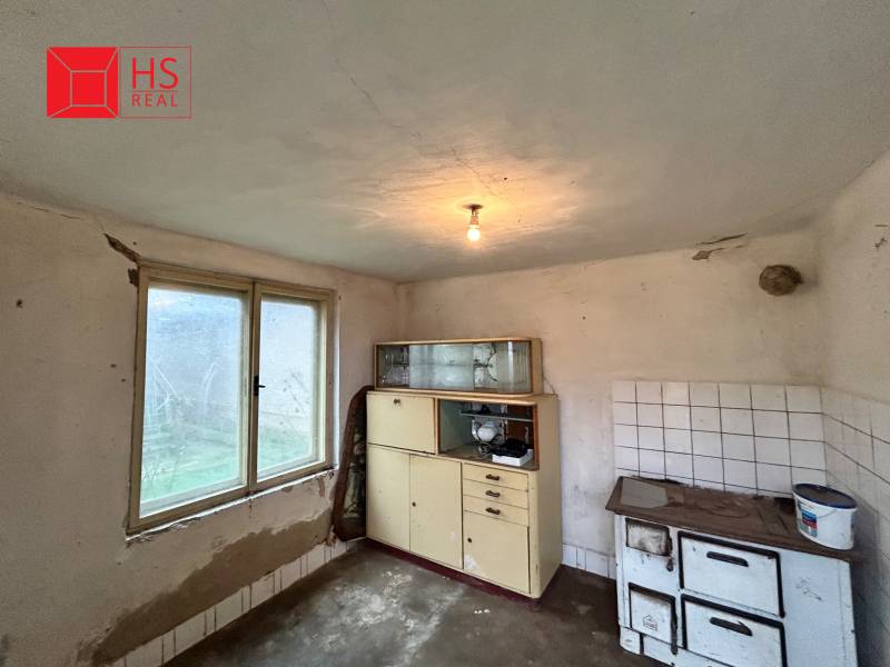 A kitchen in a family house with a ceramic stove and older furniture.