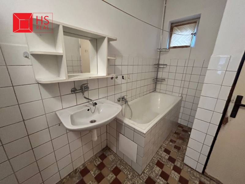 A bathroom in a family house with a bathtub, a sink, and white tiles.