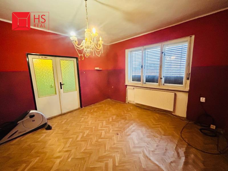 A room in a family house with a chandelier and a floor with a wooden decor.