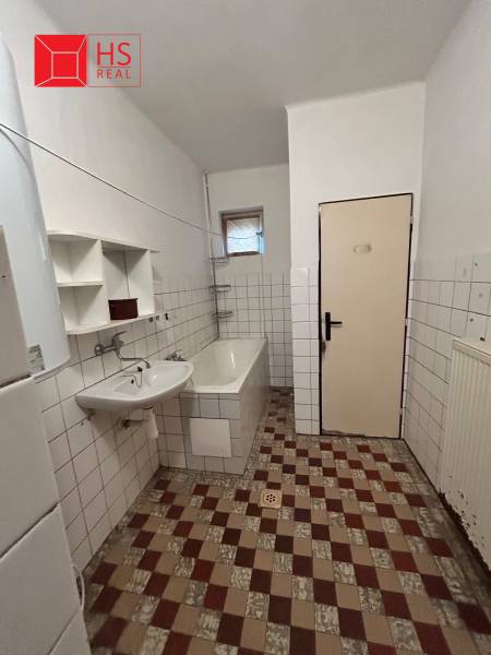 A bathroom in a family house with a bathtub and a sink, tiled with white tiles.