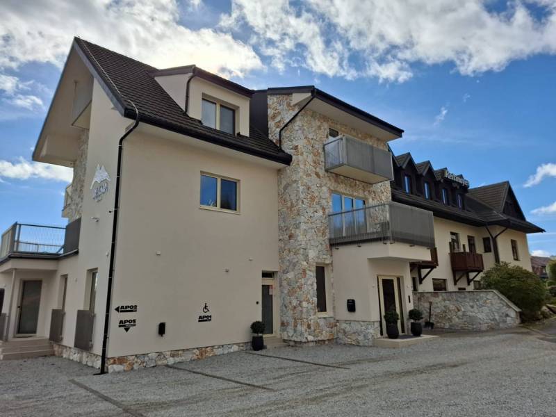 A recreational apartment in Starý Smokovec with rock elements and balconies against the backdrop of a blue sky.