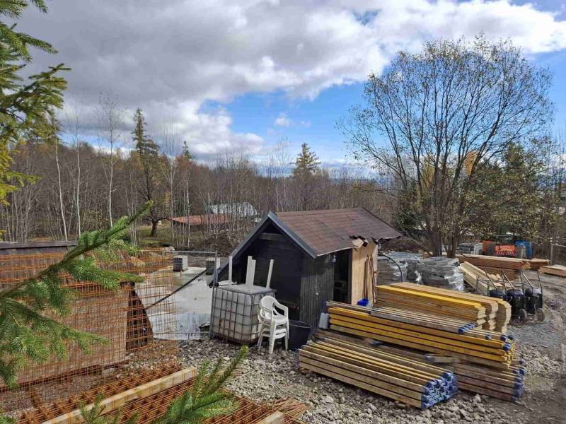 Construction site in Starý Smokovec, with piles of wood, a steel structure, and a small cabin.