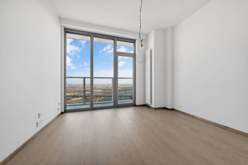 A room in a 3-room apartment with a wooden decor floor and a view through large windows.