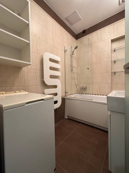 Bathroom with a bathtub, sink, and washing machine in a 2-room apartment.