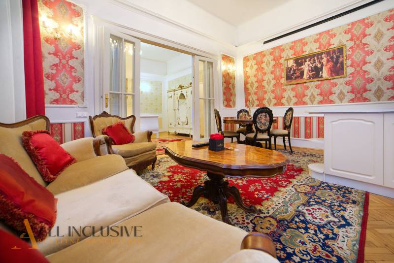 Luxurious living room with antique furniture, red cushions, carpets, and paintings.