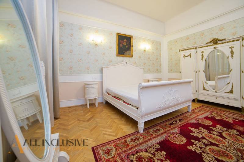 Bedroom in a 2-room apartment with wood-patterned flooring and floral wallpaper.