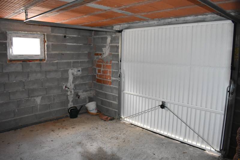 A garage in a family house in Pridraga with a concrete floor and white doors.