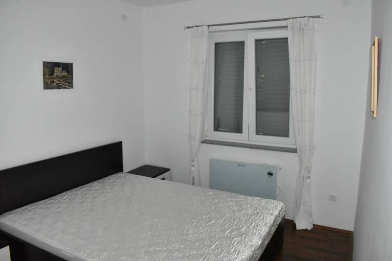 Bedroom with a bed, a painting on the wall, and a floor with a wooden decor.