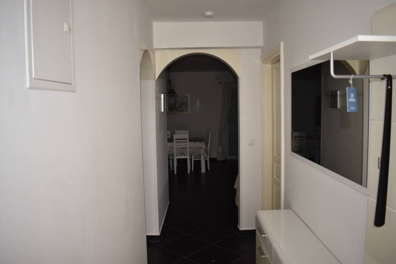 A hallway in a family house with a mirror, white furniture, and an entrance to the dining room.