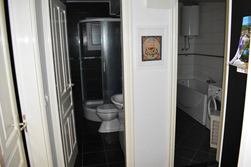 Bathroom in a family house with a bathtub, shower, and washing machine.