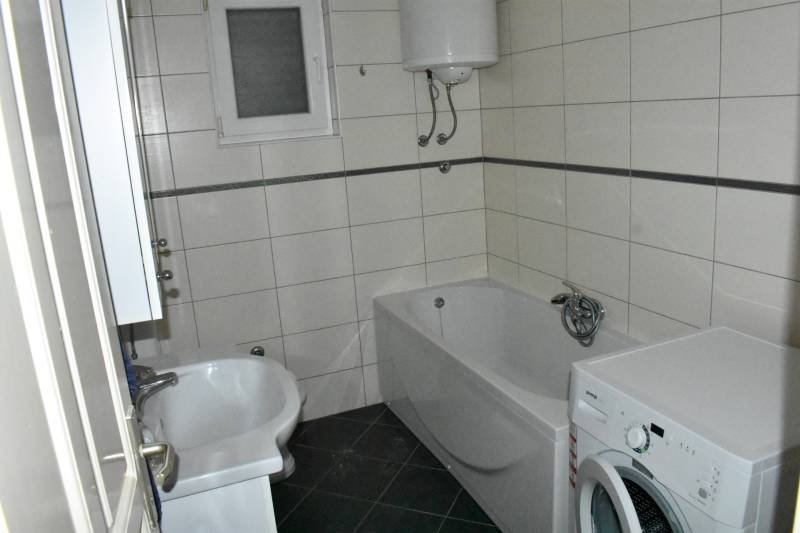 A bathroom in a family house with a bathtub, a washing machine, and a gas boiler on the wall.