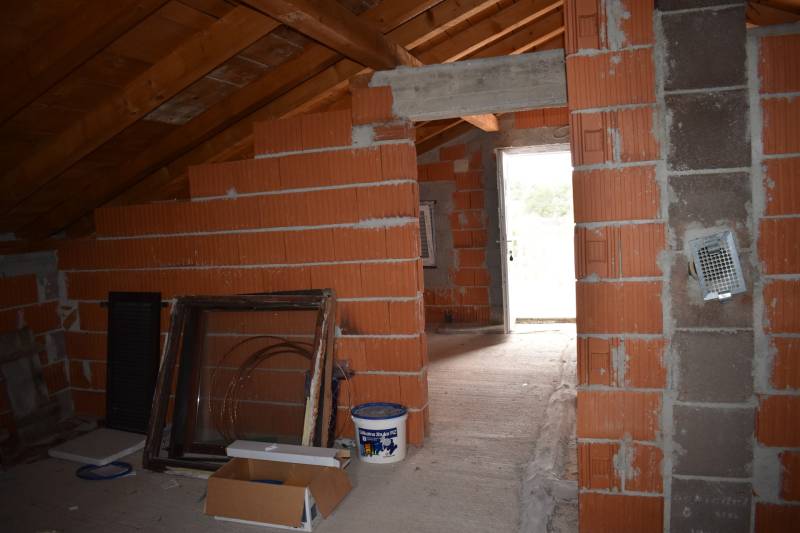 Unfinished attic interior with brick walls in a family house.