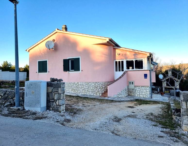 A family house in Pridraga with a pink facade and stone details on the driveway.