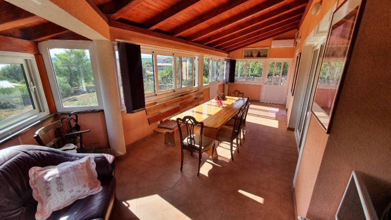 A glazed terrace in a family house with a wooden ceiling and a large table.