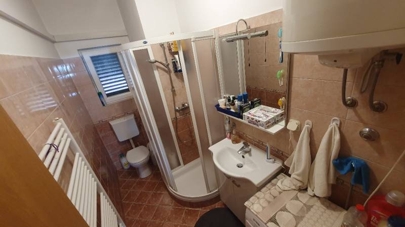 A bathroom with a corner shower and a white sink in a family house.