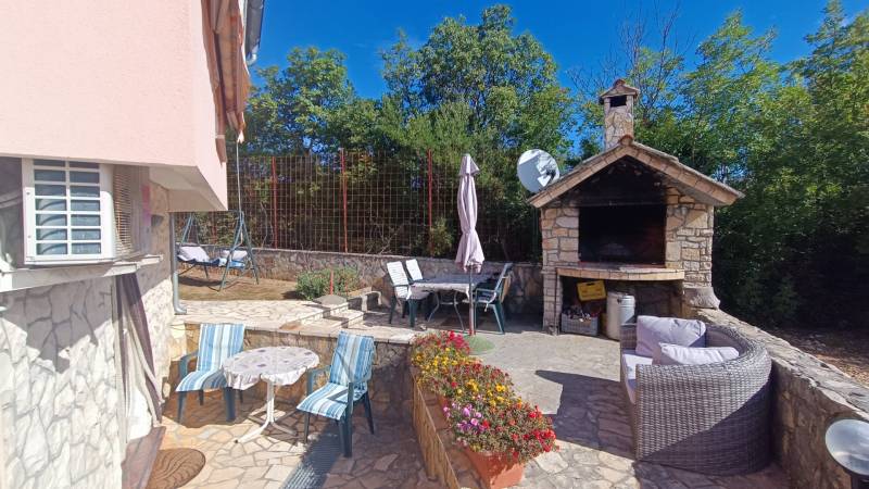 The courtyard of a family house in Pridraga with a stone grill, terrace, and garden furniture.