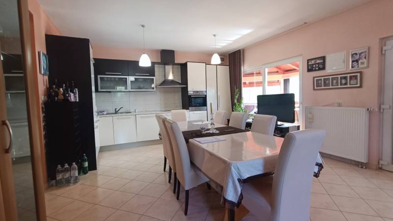 Dining area with seating and kitchen in a family house with wall decorations.