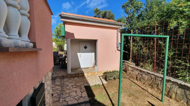 A family house in Pridraga with a stone path, garden, and white doors.