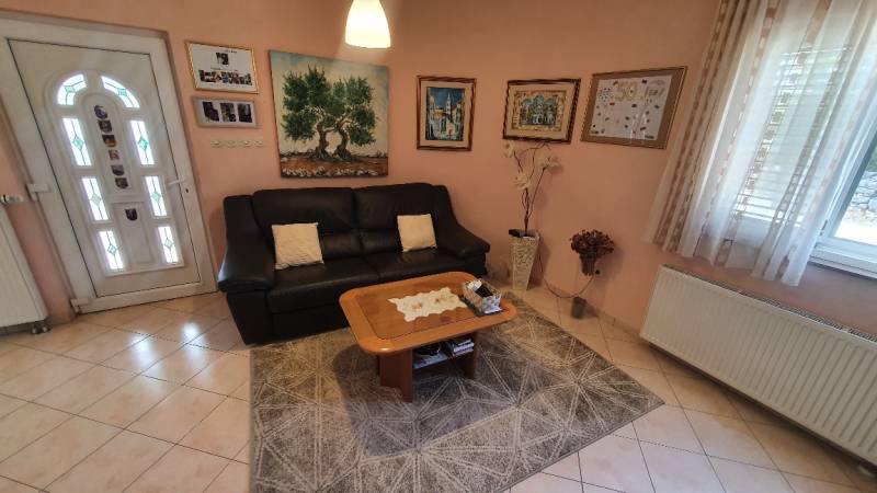 Living room in a family house with a sofa, paintings, and a table on a carpet.