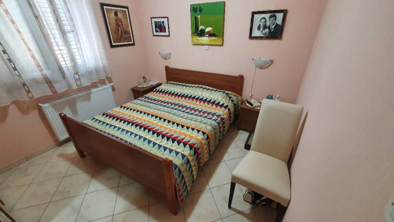 A bedroom in a family house with a colorful bedspread, decorations, and a radiator.