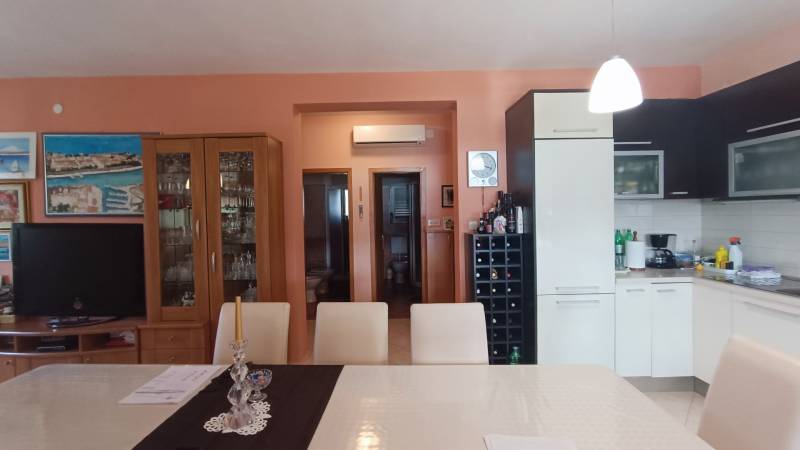 Interior of a family house with a kitchen, dining table, and a cabinet with glassware.