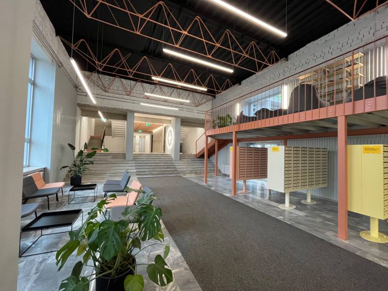 Interior with wood-patterned flooring, stairs, mailboxes, and plants in a studio apartment.