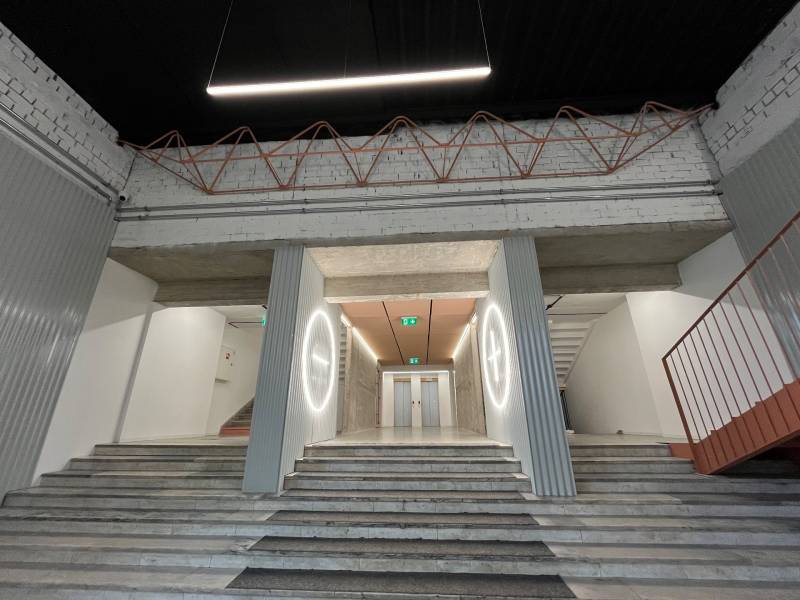 Interior with marble stairs, an area with elevators, and industrial details.