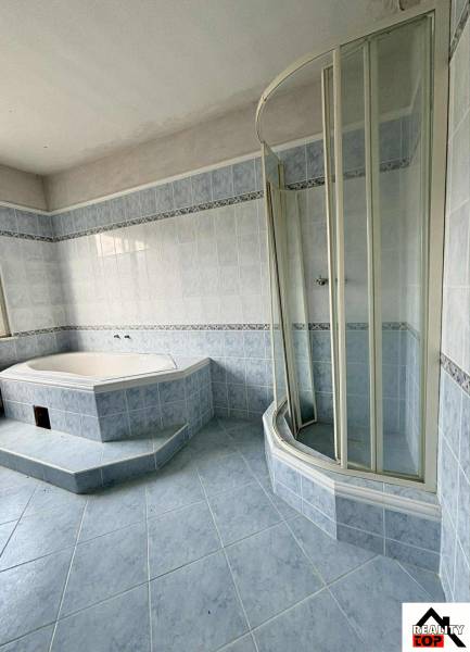 A bathroom in a family house with a corner bathtub and a shower enclosure.