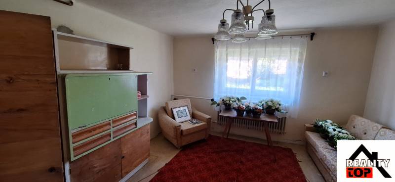 Living room in a family house with an armchair, an older cabinet, and a table with flowers.