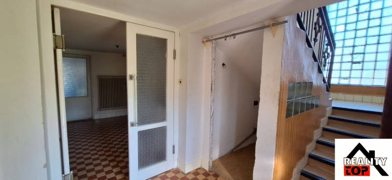 Interior of a family house with tiles, staircase, and glass partition.