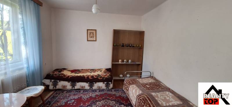 A room in a family house with two beds, a carpet, and a shelf on the wall.